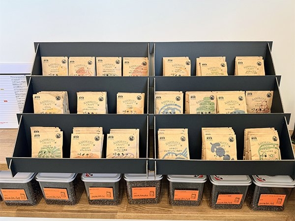 お土産も豊富にご用意しています。クラフト紙のパッケージに入ったコーヒー豆の商品がずらりと並ぶ。