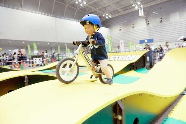 パンプジャムの様子。幼児がストライダーに跨り、笑顔でコースに挑戦している。
