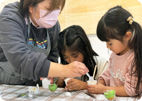 姉妹が講師から作品の作成を方法を習っている様子